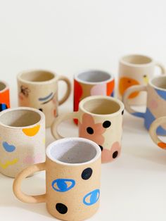 several coffee mugs with different designs on them sitting next to each other in front of a white background