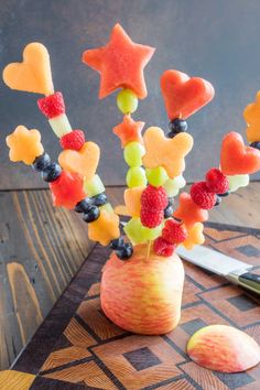 a vase filled with fruit on top of a wooden table