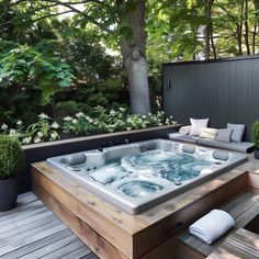 a large hot tub sitting on top of a wooden deck next to a lush green forest