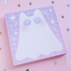 a white cat sticker on top of a pink paper with stars in the background