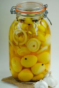 a glass jar filled with yellow onions and garlic