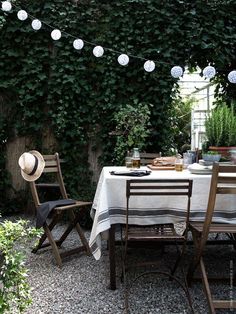 an outdoor dining area with table, chairs and lights strung from the ceiling over it