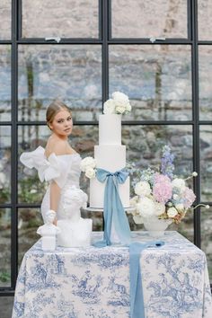 a woman standing next to a tall white cake