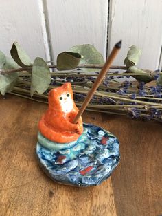 a ceramic bear sitting on top of a rock with a stick in it's mouth