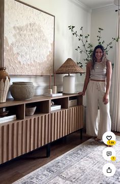 a woman standing in front of a large painting on the wall next to a tv