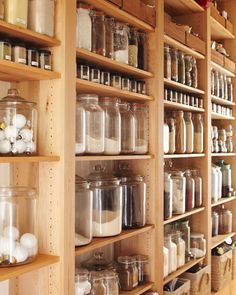 the shelves are filled with many different types of jars and containers on wooden shelving