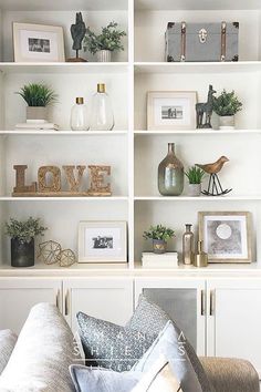 a living room filled with lots of white bookshelves covered in pictures and plants