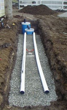 pipes are laying in the ground next to some dirt and a building with two windows