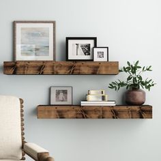 two wooden shelves with pictures on them in a living room next to a white chair