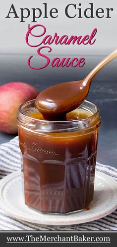 an apple cider caramel sauce in a glass jar on a plate with a spoon