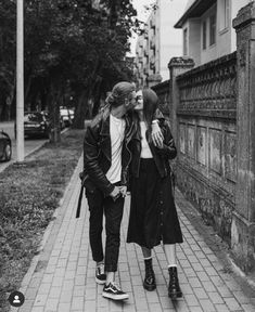 two women walking down the sidewalk in black and white