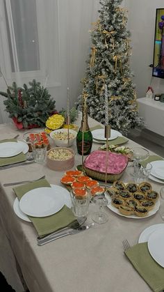 a table set with plates, silverware and christmas trees