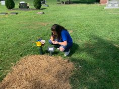 a woman kneeling down next to a pile of hay