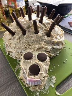 a cake with chocolate sticks sticking out of it's face on a green cutting board