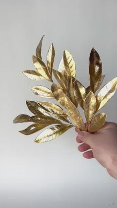 a hand is holding a gold leaf decoration