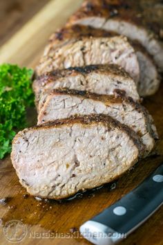 sliced meat on a wooden cutting board with parsley next to it and a knife