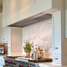 a stove top oven sitting inside of a kitchen next to white cabinets and counter tops