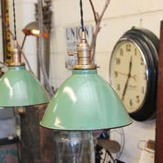 two green lamps sitting next to each other in a room with clocks on the wall