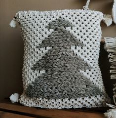 a crocheted pillow sitting on top of a wooden table next to a wall