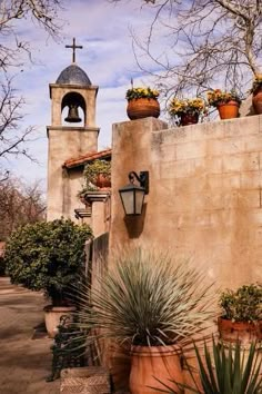 an old church with potted plants and a bell tower