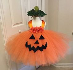 an orange and black halloween tutu skirt with pumpkins on the front, sitting on a mannequin