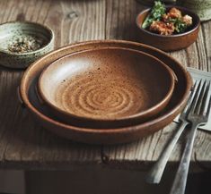 a wooden table topped with plates and bowls filled with food next to utensils