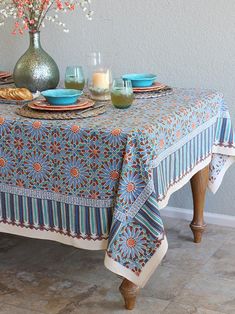 a table with plates and cups on it in front of a vase filled with flowers