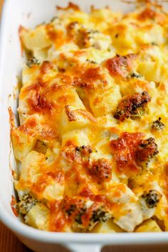 a casserole dish with cheese and broccoli in it on a wooden table