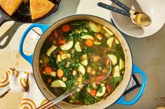 a pot filled with vegetable soup next to other dishes and utensils on a table