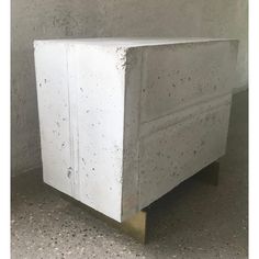 a white cabinet sitting in the middle of a room next to a wall with concrete on it