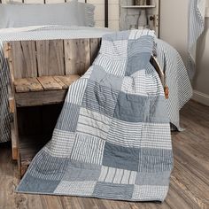 a bed with a blue and white checkered blanket on it next to a wooden bench