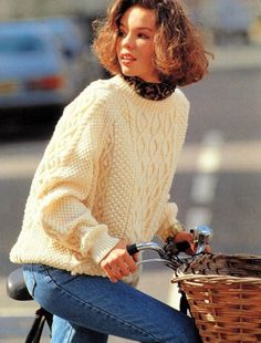 a woman riding a bike with a basket on the handlebars in front of her