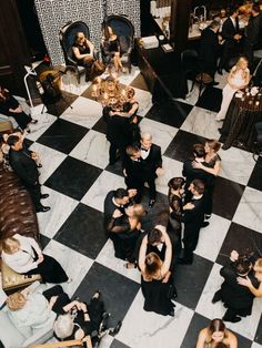 a group of people standing around each other on top of a black and white checkered floor