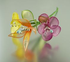 two glass flowers with pearls on them are sitting next to each other in front of a reflective surface