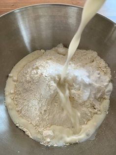 a metal bowl filled with flour and milk