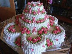 a large white cake with pink flowers and ribbons on the top tier is sitting on a table