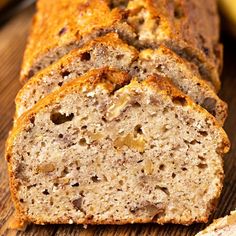 sliced loaf of banana nut bread sitting on top of a wooden table next to two bananas