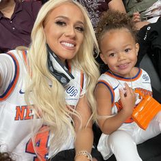 a woman holding a child in her arms at a basketball game with other people watching