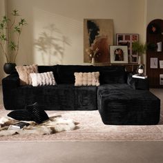 a living room with black couches and rugs on the floor in front of a window