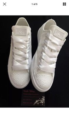 a pair of white tennis shoes sitting on top of a black table next to a card