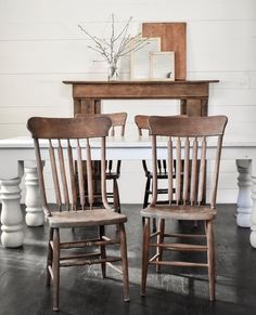 two wooden chairs sitting next to each other in front of a white table and fireplace