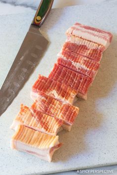 sliced meat sitting on top of a cutting board next to a knife