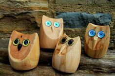 three wooden owls with blue eyes are sitting on a tree branch in front of a stone wall