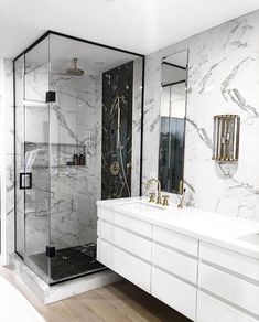 a bathroom with marble walls and flooring in white, black and gold colors is shown