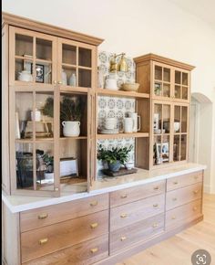 a kitchen with wooden cabinets and white counter tops in front of a wallpapered backsplash