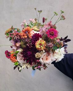 a person holding a bouquet of flowers in their hand on the side of a building