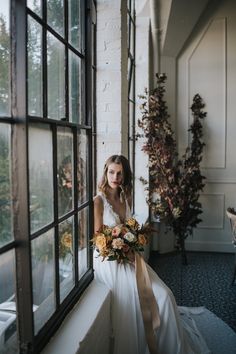 a woman sitting on a window sill holding a bouquet