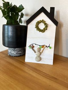 a small house with a wreath on the front and a potted plant behind it