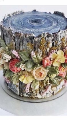 there is a cake decorated with flowers and leaves on the top of this tree stump