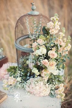 a birdcage filled with flowers and greenery